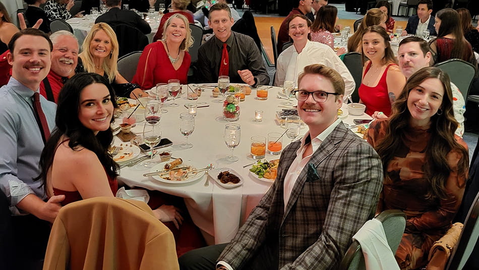 a group of smiling couples at a circular table