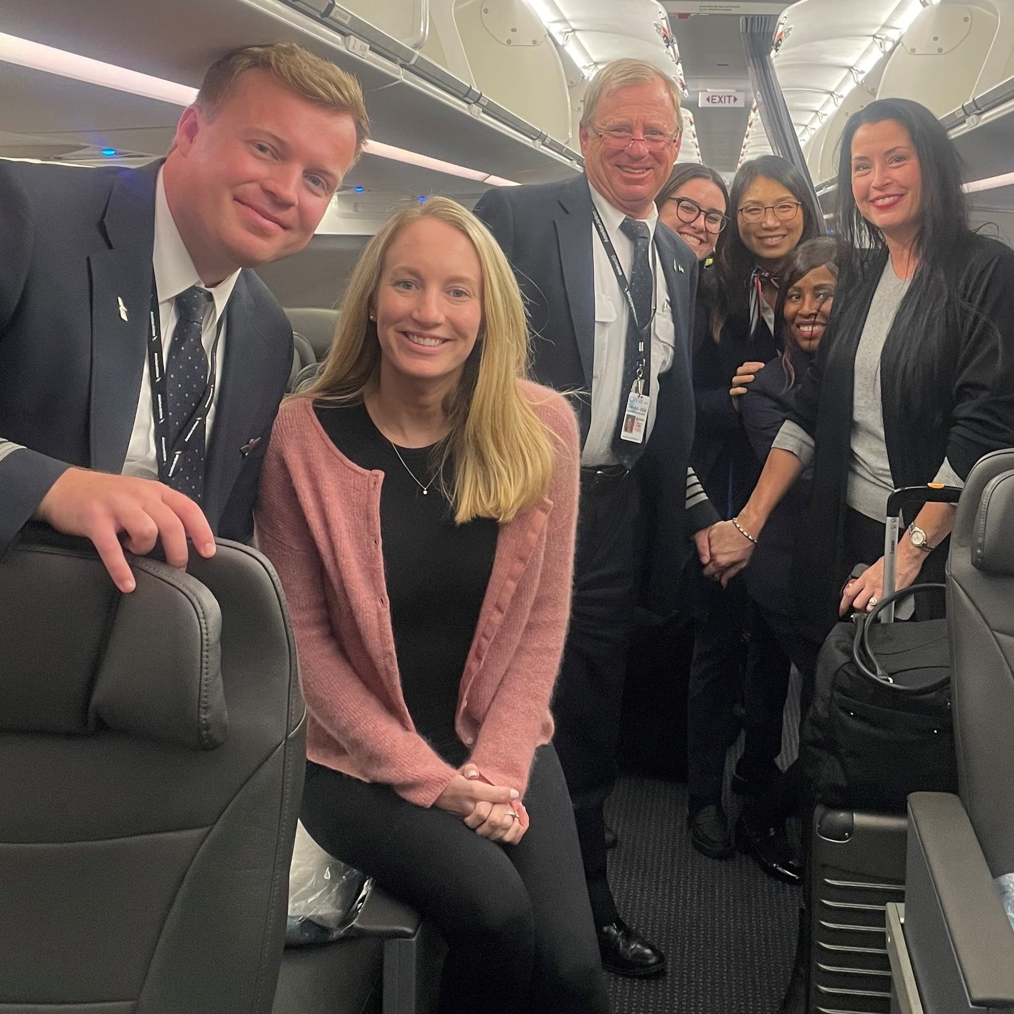 two smiling pilots with their wives plus three flight attendants